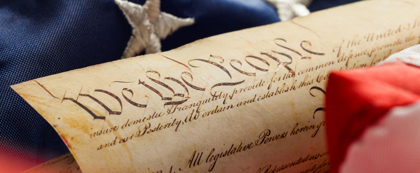 Close view of the U.S. Constitution's We the People preamble against an American flag