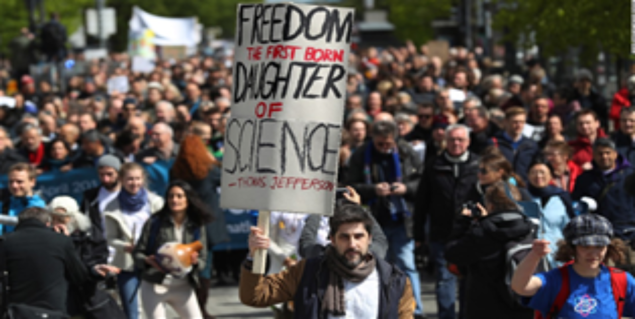 Marchers at the March for Science; a hand-lettered sign quotes Thomas Jefferson: Freedom, the first born daughter of science